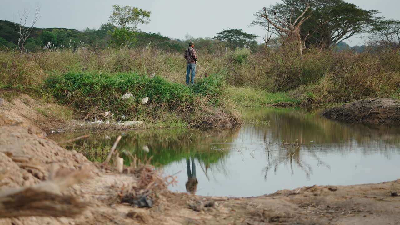 Hombre de pie junto a un lago rodeado de naturaleza