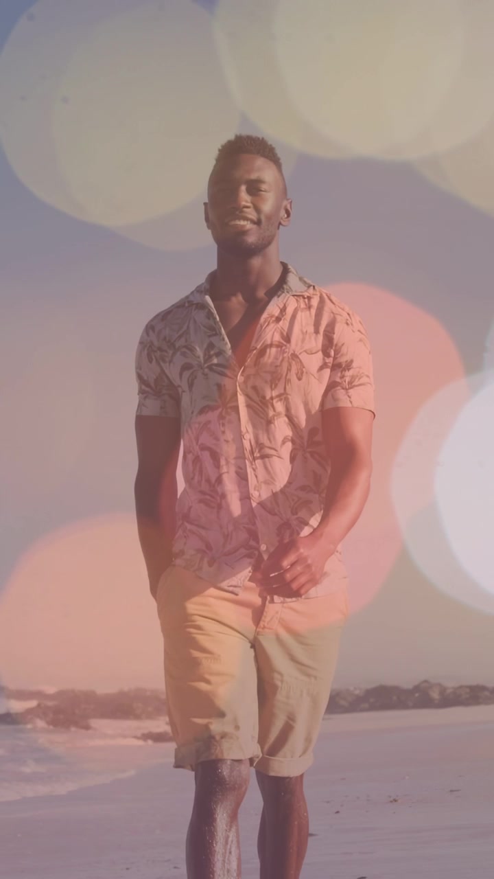 Vertikal video: Mand begynder at gå på stranden, bevæger sig tættere på, mens bokeh-overlay viser en skjorte til reklamer.