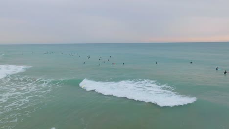 novice surfer struggles to stand up on blue foam board on shoulder of small wave