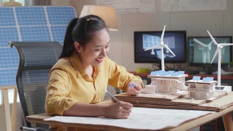 asian woman sketch house with solar panel on the blueprint while holding it in hand