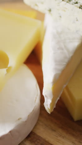 video close up of assorted hard and soft cheeses on wooden chopping board