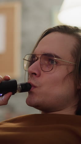 handsome sports fan smokes e-cig watching basketball championship in apartment closeup slow motion. using internet sources to analyse match results