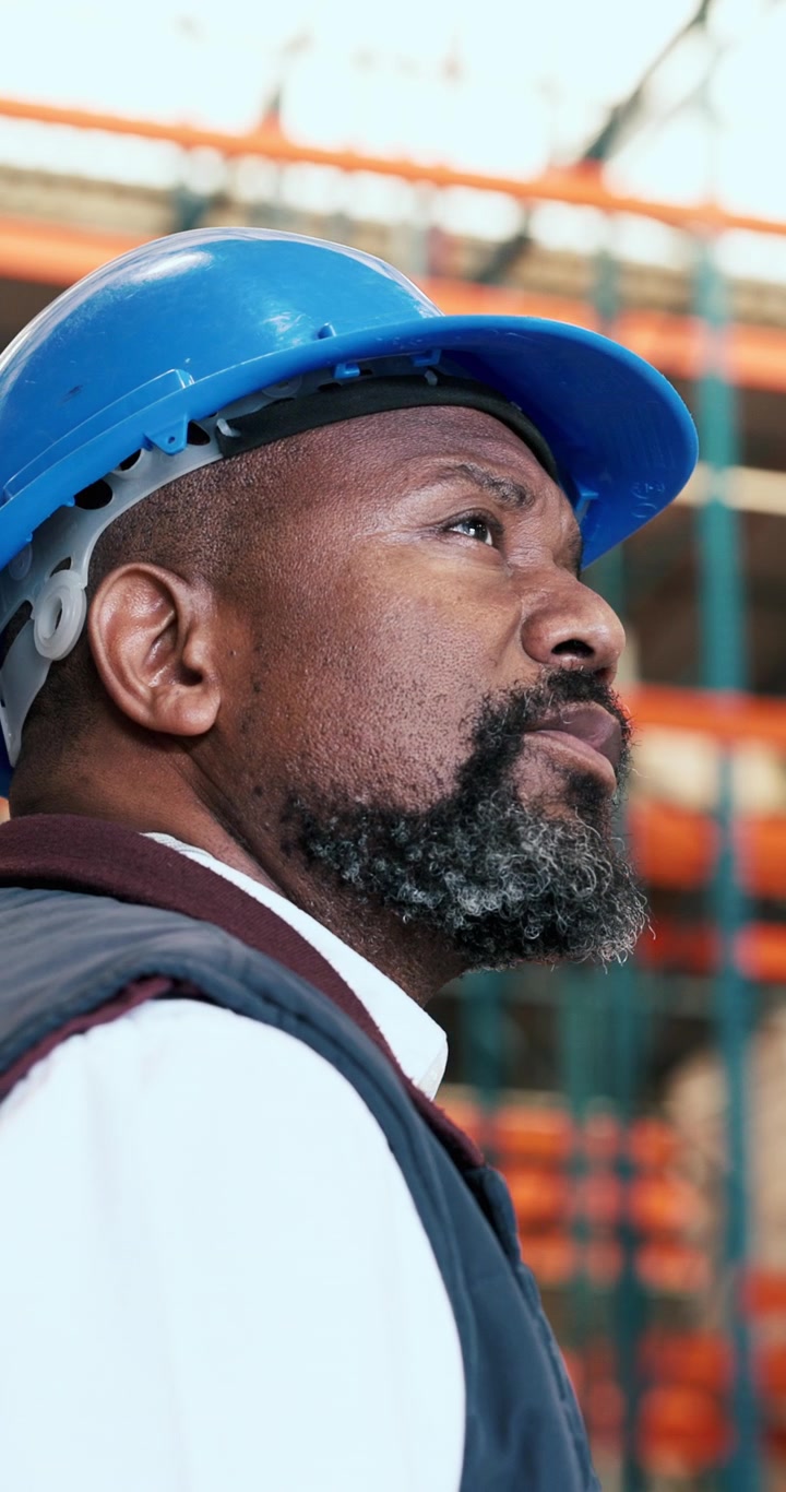 Warehouse Manager Wearing Hard Hat Looking Up at Inventory
