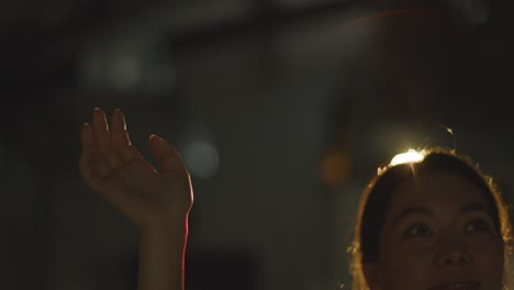 woman visiting and interacting with immersive art exhibition backlit by light from projector