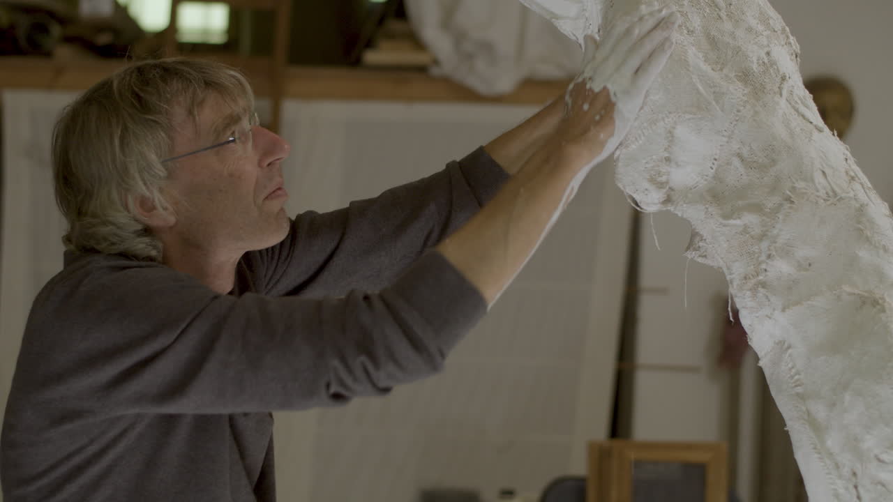 Artist forming and adjusting plaster sculpture