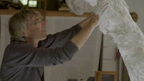 Artist-forming-and-adjusting-plaster-sculpture
