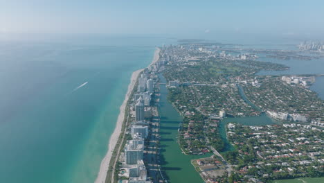 City-on-ocean-coast-from-height.-Stripe-of-sand-beach-along-modern-tall-apartment-buildings.-Miami,-USA