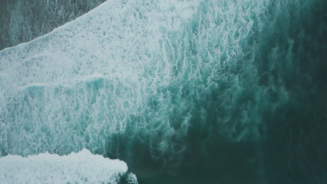 Aerial view of deep blue white cap waves crashing on shore in Kauai, Hawaii