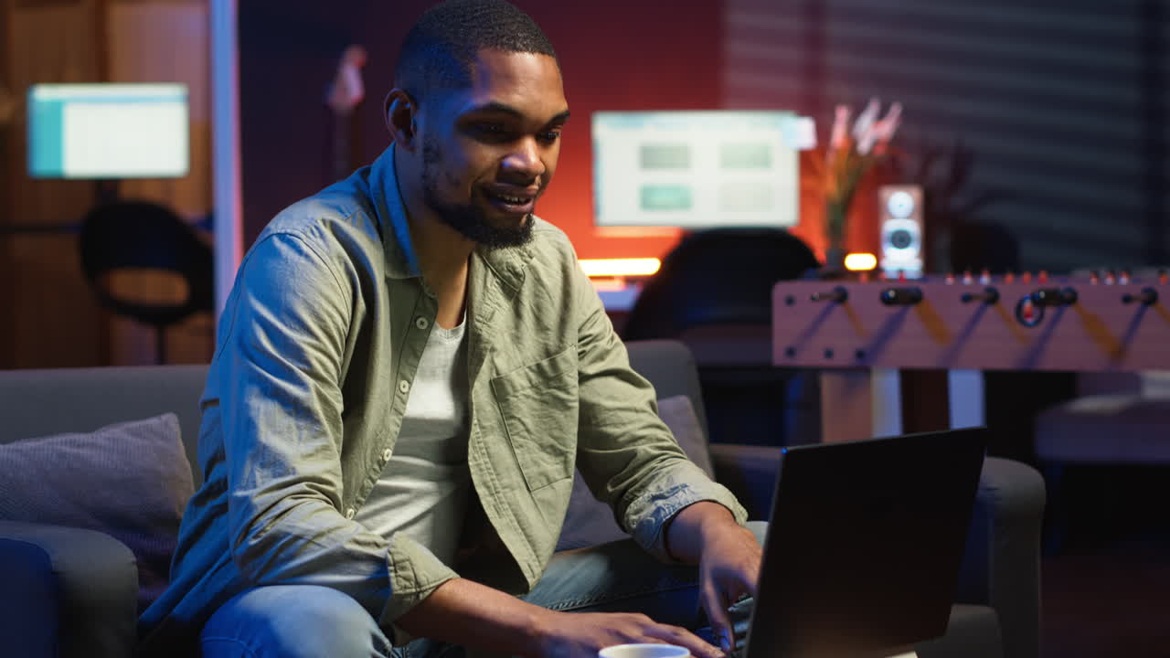 Vertical Video Young black adult working on his freelance tasks in the living room