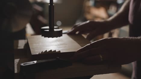 Carpenter placing wood board under workshop drilling machine, cinematic light
