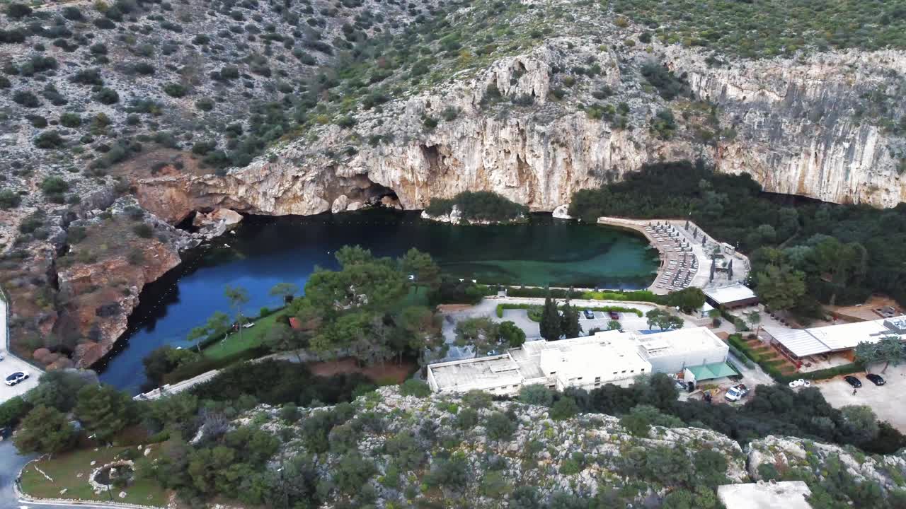 High angle bird&rsquo;s-eye view of the submerged lake of Vouliagmeni in Athens, Greece with stunning surrounding cliffs and a highway above the lake | 4K