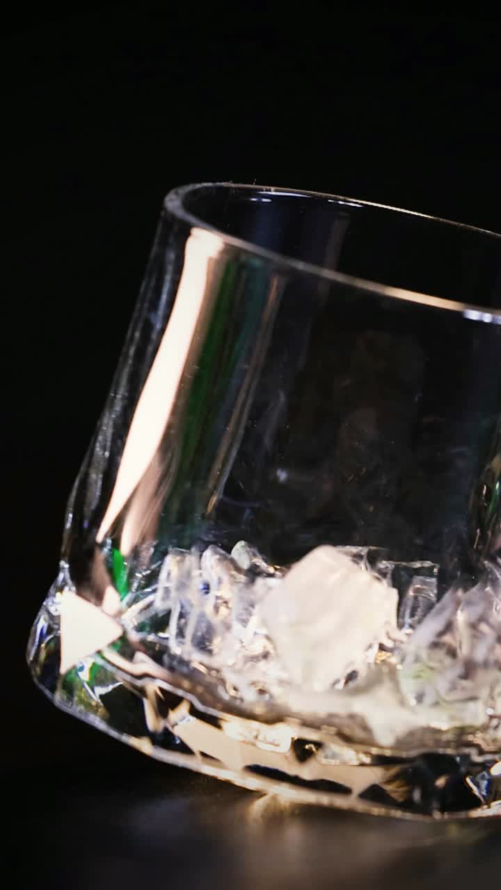 la mano deja caer cubos de hielo en un vaso