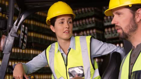 workers sitting in forklift and talking to each other in warehouse