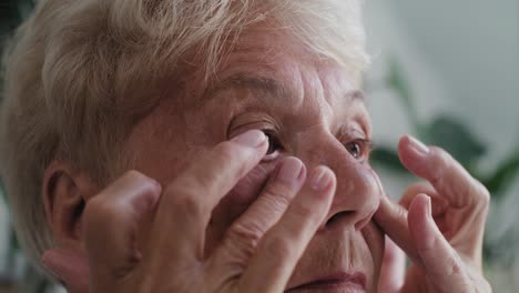 close up of senior woman checking skin condition around the eye area