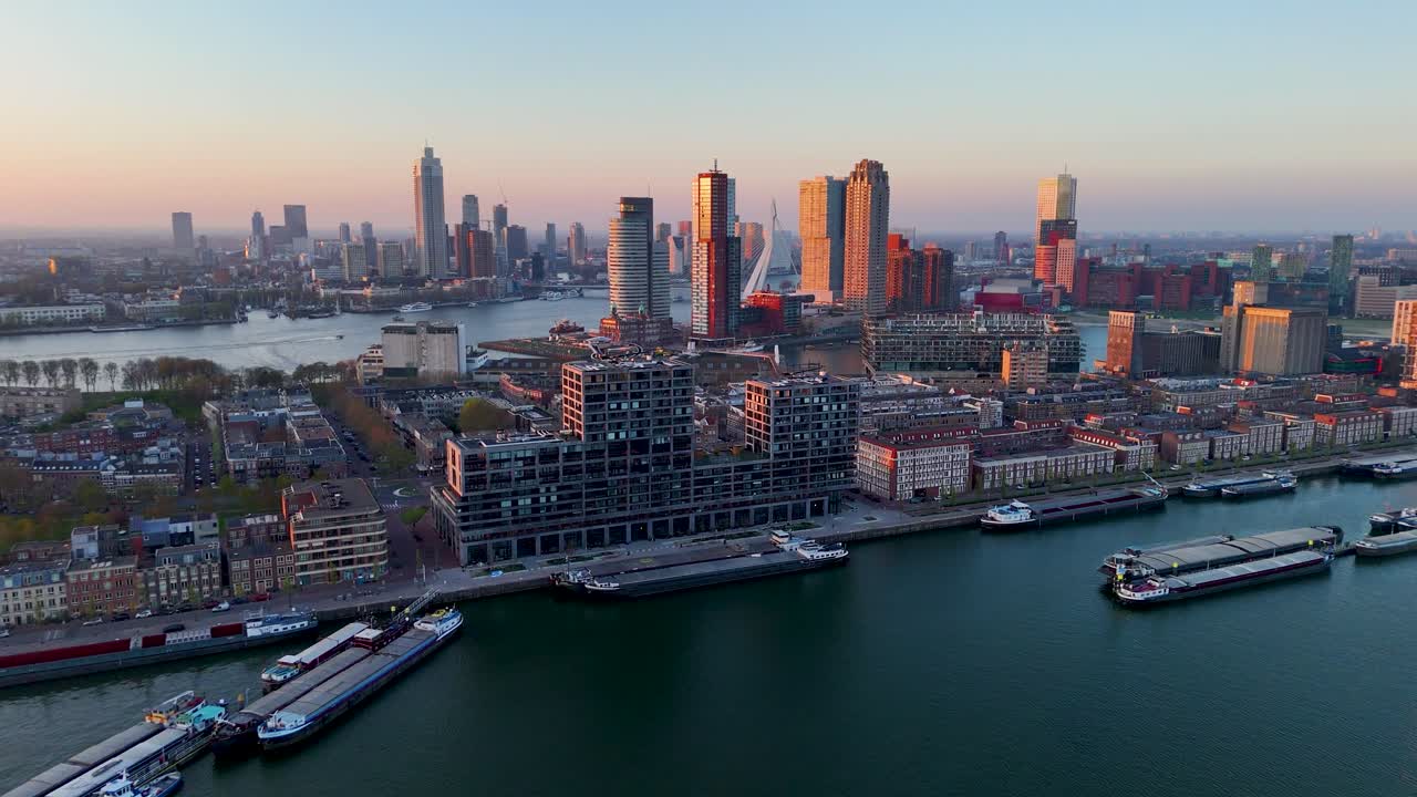 Beautiful aerial sunset view of Rotterdam city showing modern skyline reflecting warm light with cargo ships on Maas River and contemporary architecture creating vibrant urban landscape