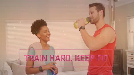 animation of train hard keep fit text over diverse couple drinking water at home