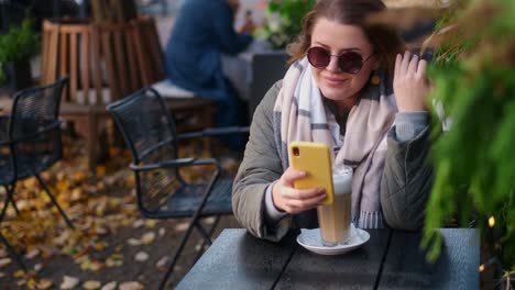 woman enjoying a latte in an outdoor cafe during autumn