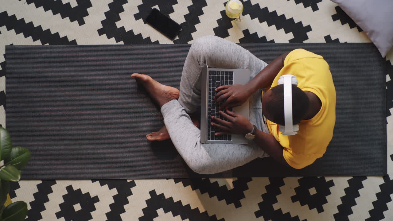 Uomo Afroamericano con le Cuffie che Digita sul Laptop a Casa