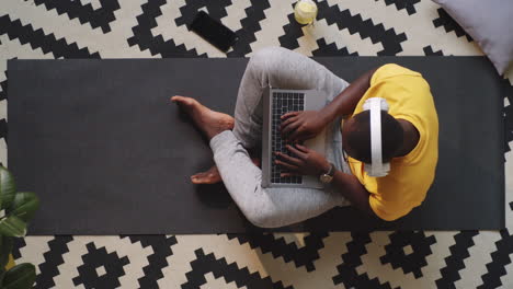 afro-american man in headphones typing on laptop at home