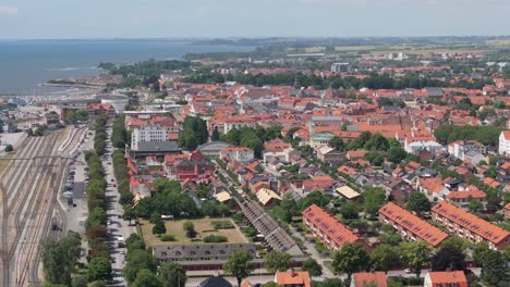 City-Ystad-skyline-with-orange-rooftops-and-railroad-station,-aerial-sideways