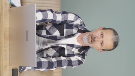 Vertical-video-of-Old-man-looking-at-laptop-in-amazement.