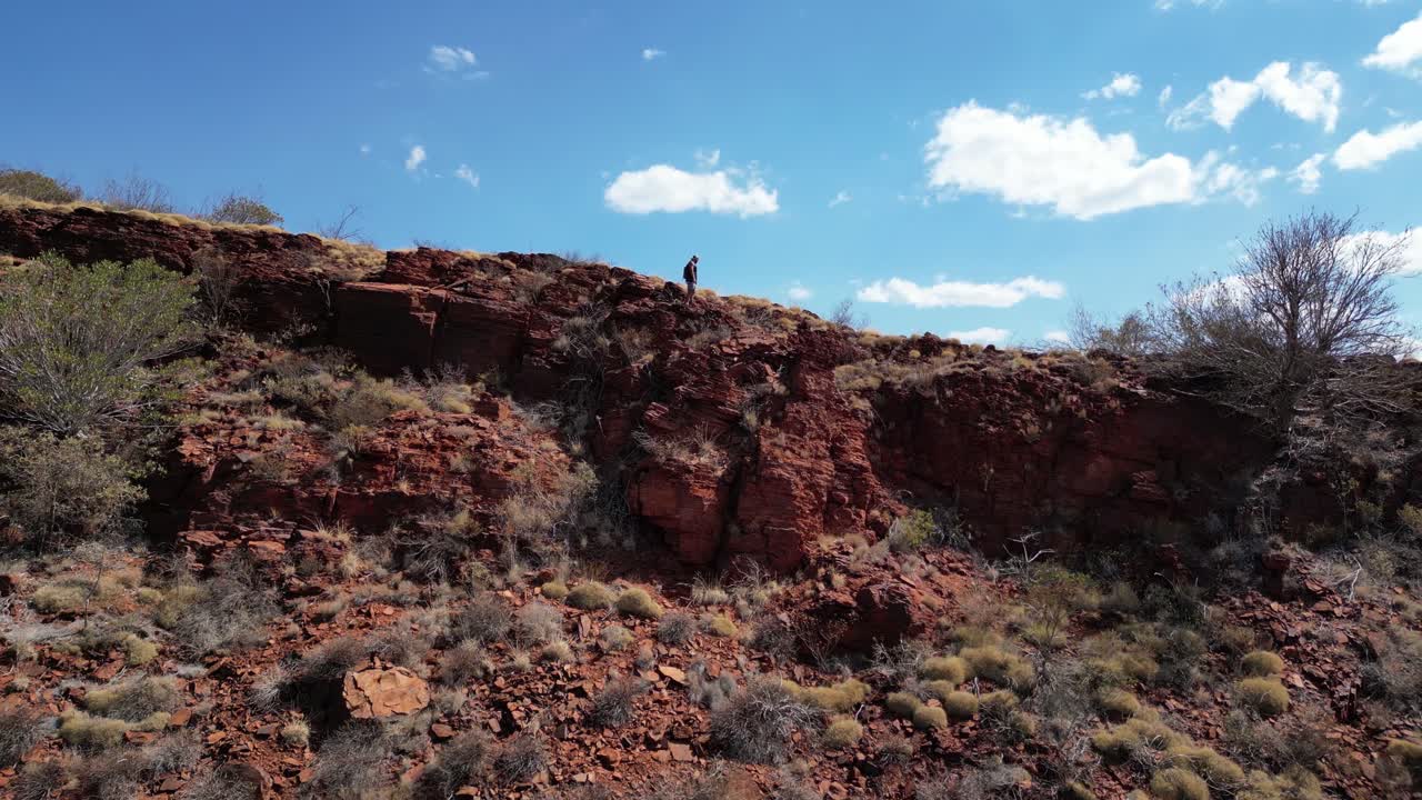 vista aérea de un excursionista en el borde de las montañas rojas en el parque nacional de kariini durante un día soleado en australia