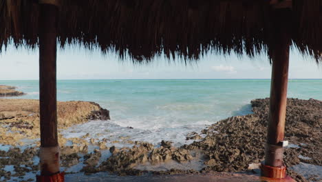 establishing shot of caribbean coast with a hut in the foreground and the horizon sea in the background