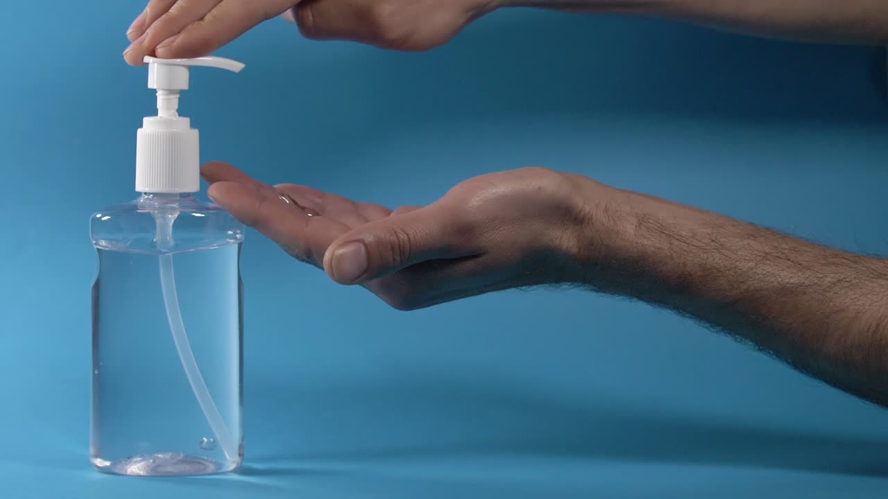 uso de gel desinfectante antibacteriano para manos contra fondo azul, cámara lenta