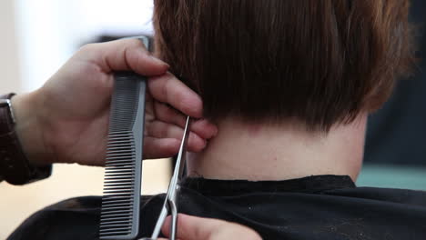 Nahaufnahme-Der-Hände-Eines-Friseurs,-Der-Haare-Mit-Einer-Schere-In-Einem-Friseursalon-Schneidet