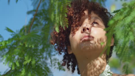 primer plano facial de ángulo bajo de una niña de ojos marrones en un parque con hojas en primer plano