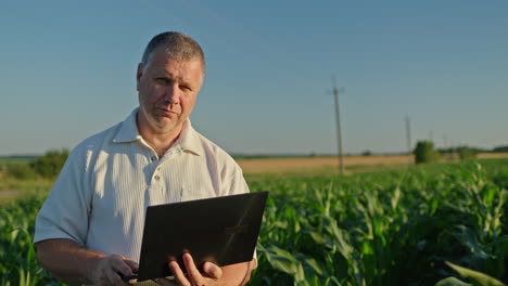 farmer using a laptop in a cornfield