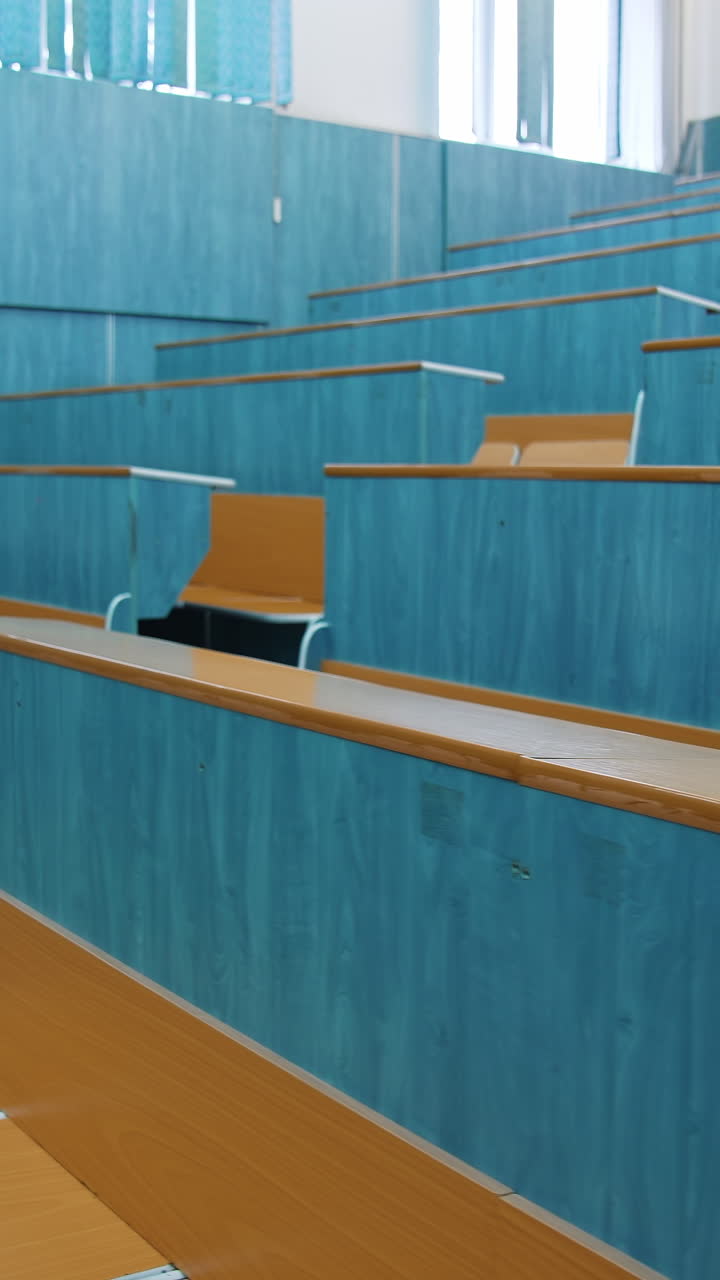 Empty lecture hall. Auditorium with wooden desks and chairs at educational center. Conference hall without students in the university. Vertical video