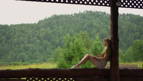 pretty woman writer works on laptop sitting on terrace