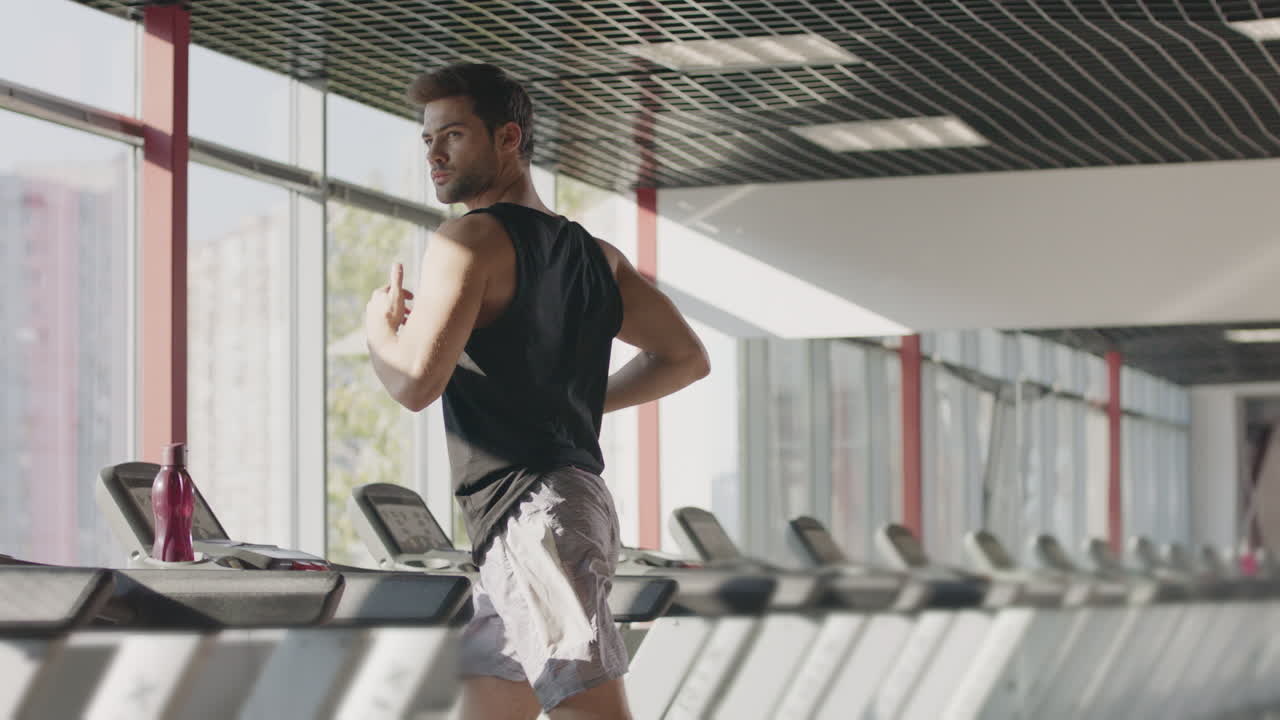 Runner man training on treadmill machine at workout in fitness center