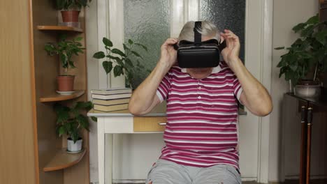 senior grandfather putting on virtual headset glasses and watching 3d video in 360 vr helmet at home