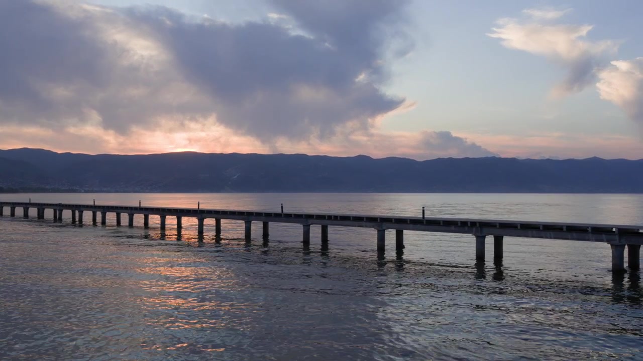 アルバニアの自然が広がるオフリド湖の桟橋。山々のスカイラインに沈む午後の夕日。