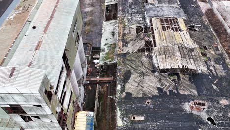 Holes in the roof of a warehouse in old abandoned chemical plant. Territory and buildings in decay. Aerial perspective.