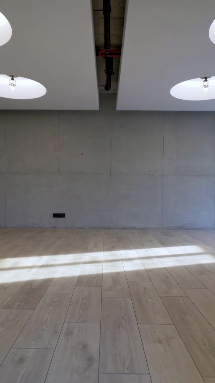 Vertical video: Filming steady cam in studio, empty room showing exposed pipe and sunlight shifting