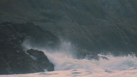 incredible dramatic waves crashing onto rocks on welsh gower coast in slow motion with steep cliffs in background. mother nature displaying full power. prores 4k.