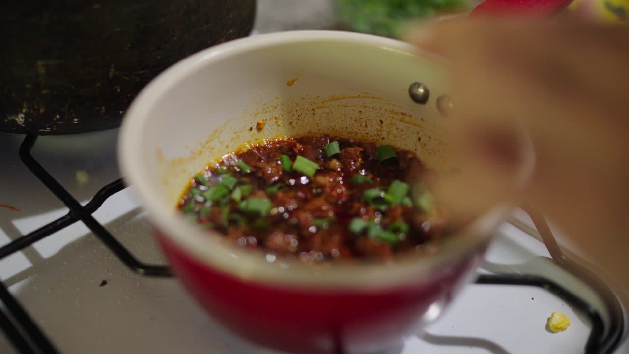 A rich fried sauce simmers in a pot on the stove, key to authentic Locro flavor.