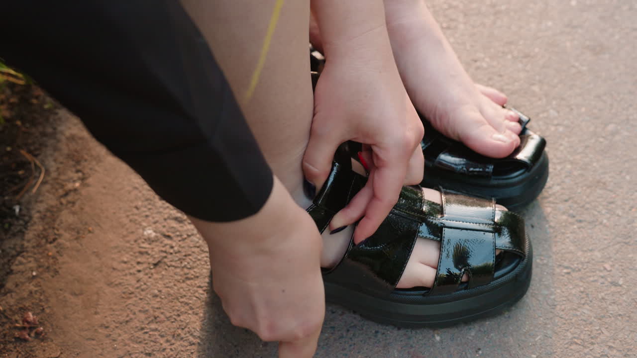 친구가 샌들을 신도록 도와주고, 저녁 산책 전에 샌들을 조절하는 동안 부드럽게 지지해 줍니다. 친한 동반자가 서로 저녁 산책을 떠나기 위해 신발을 신는 것을 도와주는 자상한 모습입니다.