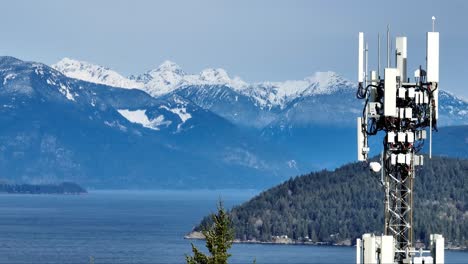 telecommunications tower antenna with howe sound and snowy mountains in the background in bc, canada