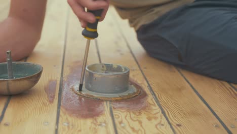 Carpenter-unscrewing-screws-from-roof-vent-on-wood-boat