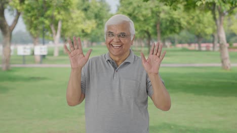 Happy-Indian-old-man-saying-hello-and-waving-in-park