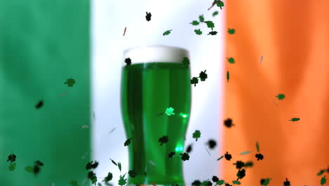 shamrock confetti falling beside pint of green beer