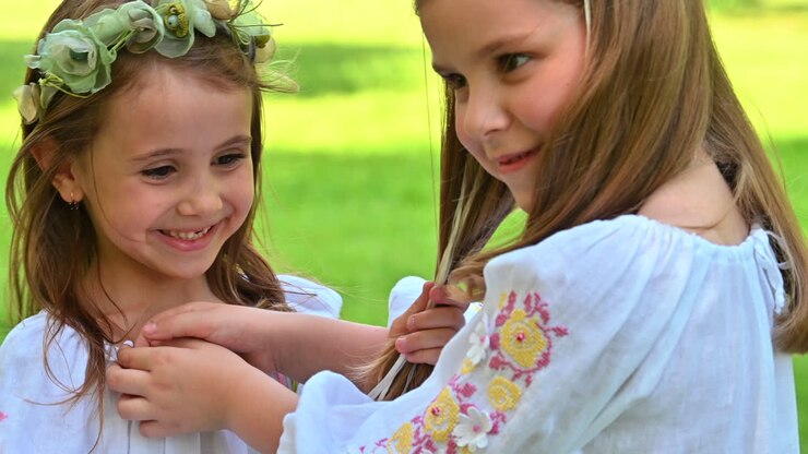 Niñas pequeñas jugando en un parque con vestidos tradicionales de verano