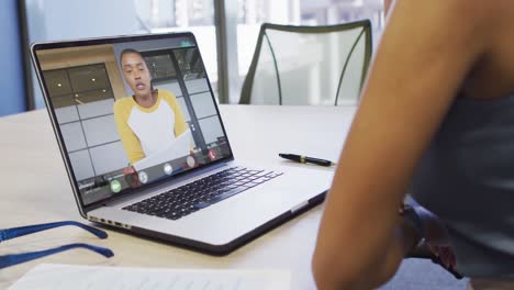 Video-of-biracial-woman-having-video-call-on-laptop-with-biracial-female-coworker