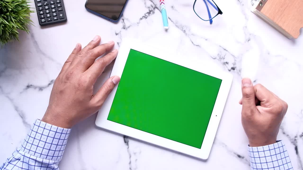 человек, использующий планшет с зеленым экраном на мраморном столе