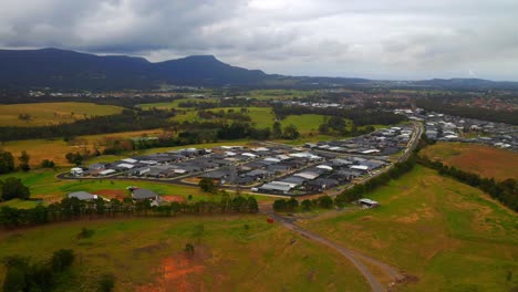 Vista-Aérea-De-Casas-De-Pueblo-Rodeadas-De-Coloridos-Campos-Cerca-De-Wollongong,-Nsw,-Australia