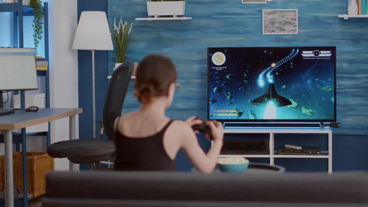 Ragazza del giocatore che tiene il controller wireless che gioca allo sparatutto in prima persona del videogioco per console in tv